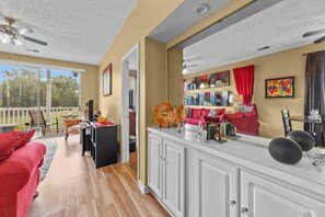 A spacious living area with a kitchen counter, a red sofa, and a dining area with a table and chairs. - River Oaks 48-D (Myrtle Beach)
