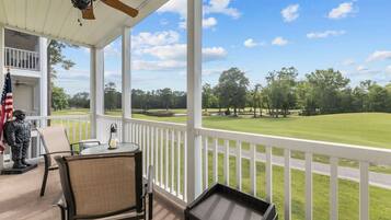 A covered porch with a view of a golf course, a statue, and a flag.