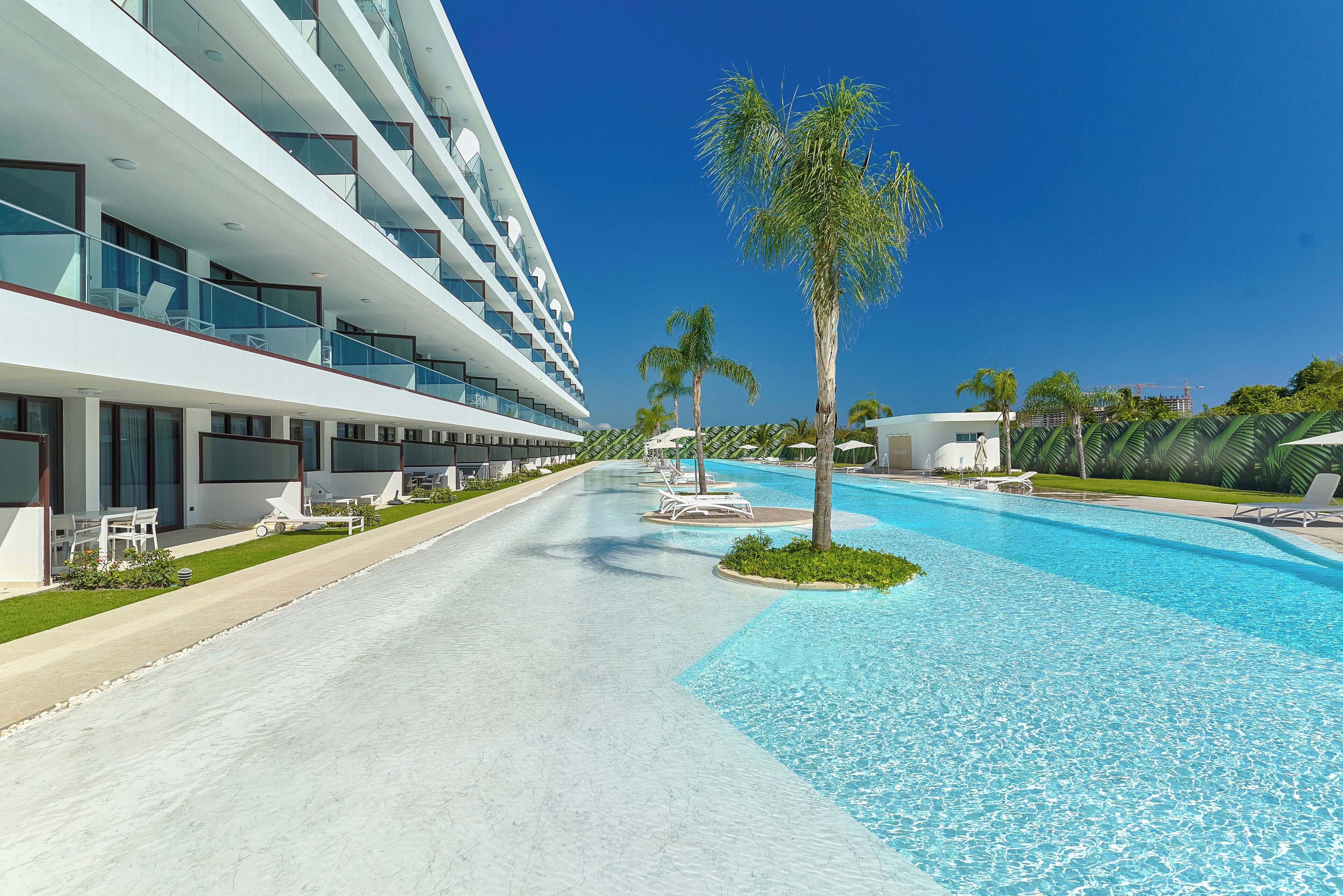 Un hôtel moderne doté d’une piscine, de nombreux balcons et de palmiers.