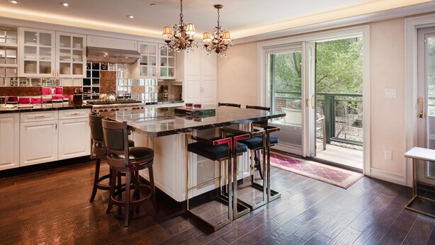 Cozinha moderna com ilha central, banquetas e um lustre.