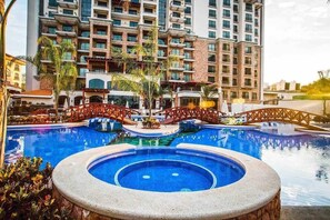 A hotel with a large central pool, multiple balconies, and a bridge connecting different sections. - Oceanfront 3BR | 9th-Floor Views | Croc's (Jacó)