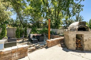 Relax on the patio surrounded by trees, featuring a barbecue grill, sofa, and comfortable seating.