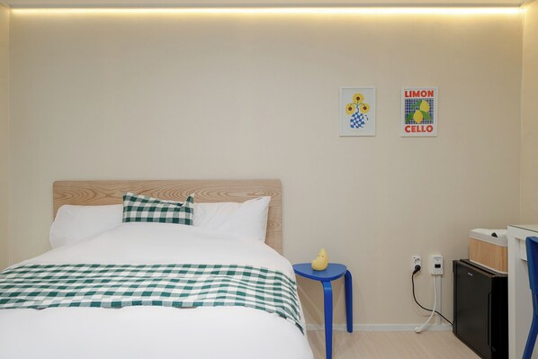 A hotel room with a bed, a small table, a wall-mounted TV, and a wall art piece. - Mutal Stay (Seoul)