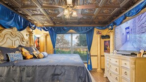 Un dormitorio con una cama grande, techo decorado y un televisor sobre una cómoda.