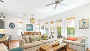 Ein geräumiges Wohnzimmer mit einer Couch, einem Couchtisch und einem Deckenventilator.