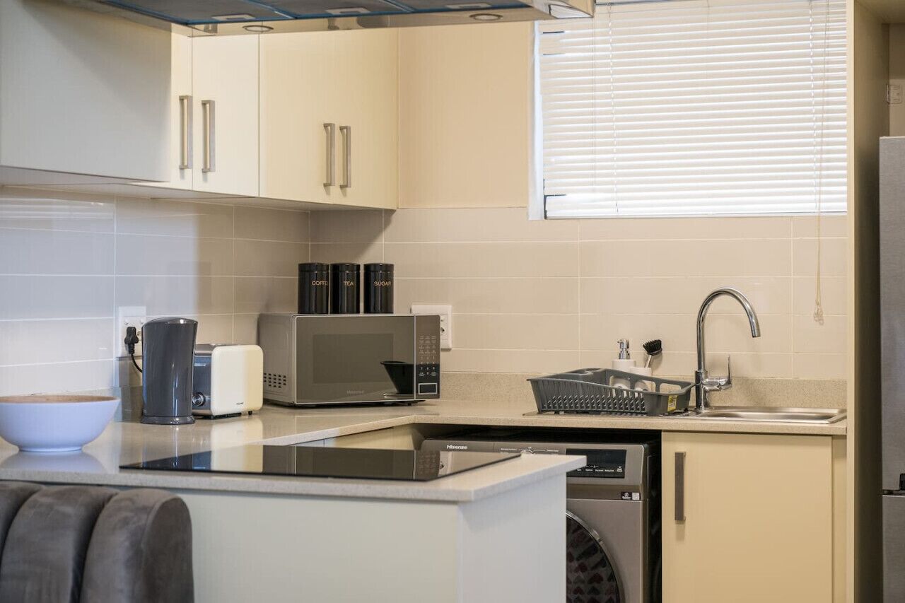 A compact kitchen with a microwave, toaster, coffee maker, and dishwasher.