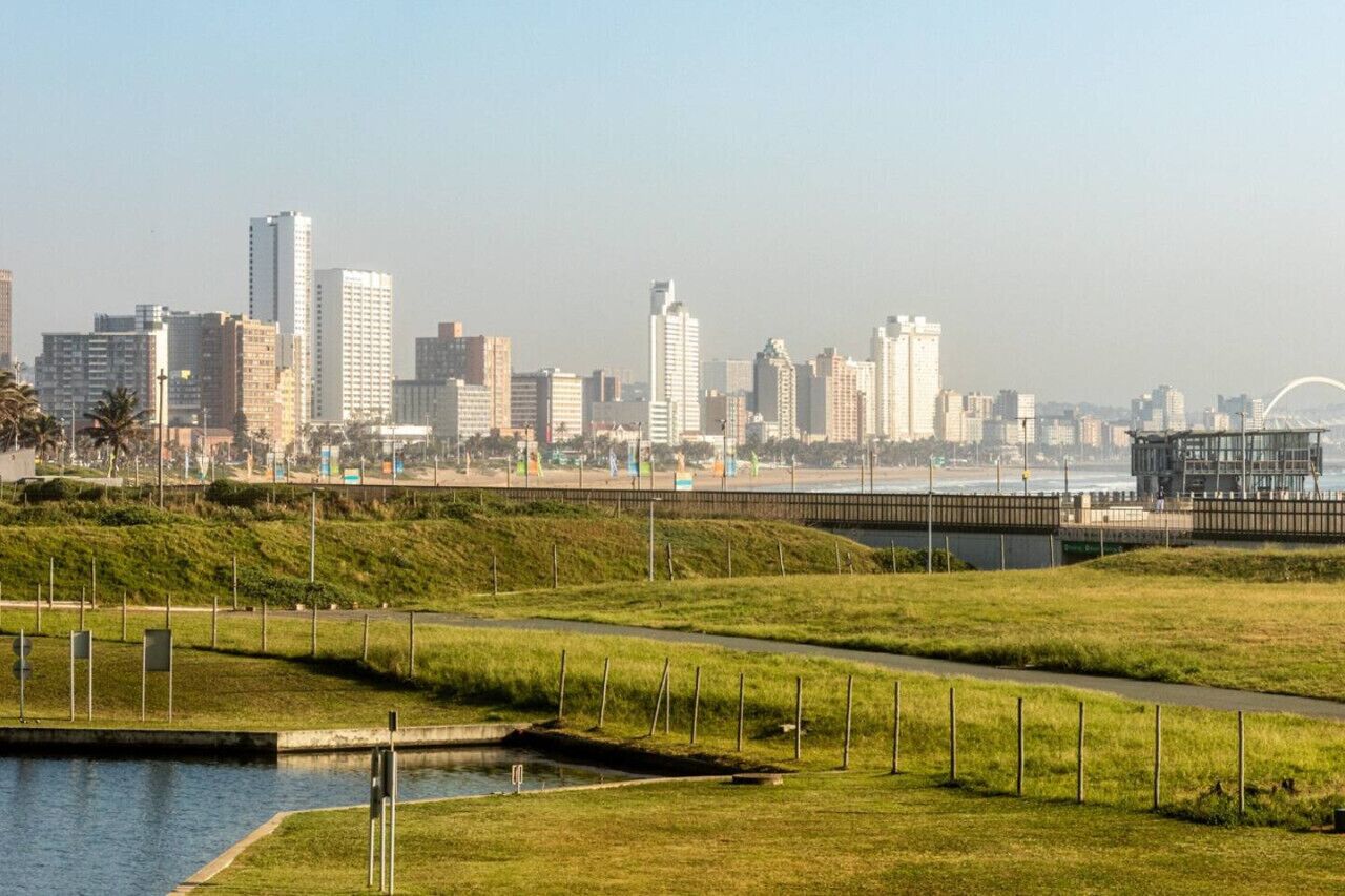Eine Stadtlandschaft mit modernen Wolkenkratzern, einer Uferpromenade und einer Brücke.