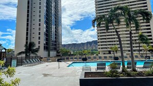 A hotel with a swimming pool, palm trees, and mountains in the background. - Part Ocean View, Beach Theme 23rd Fl, Free Parking with WiFi, AC  (Honolulu)