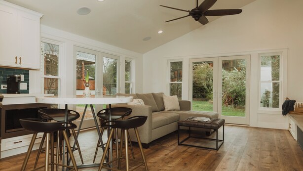 A spacious kitchen with a dining area, a ceiling fan, and large windows.