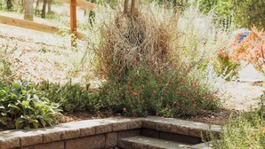 A stone staircase leading up to a wooden deck surrounded by lush greenery and flowering plants.