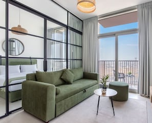Enjoy a city view from the large window, relax on the green sofa, and dine or work at the small table with a chair.