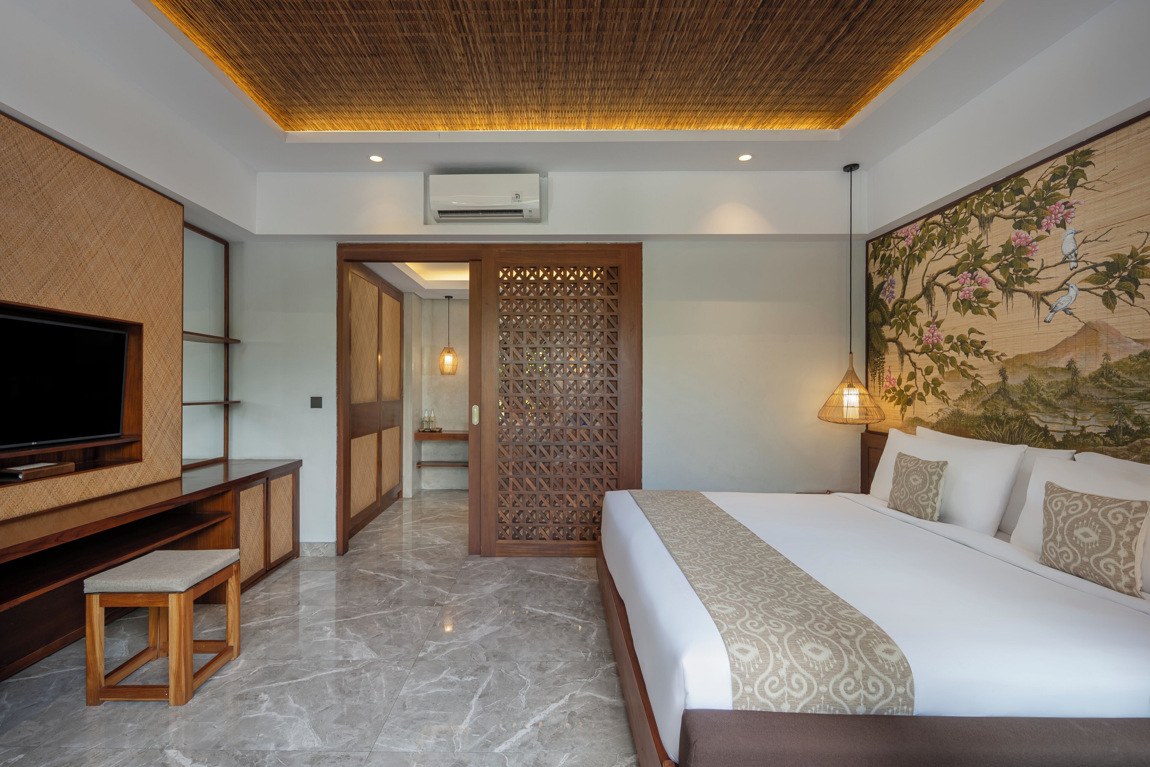 A modern hotel room with a large bed, a TV, and a decorative wall.