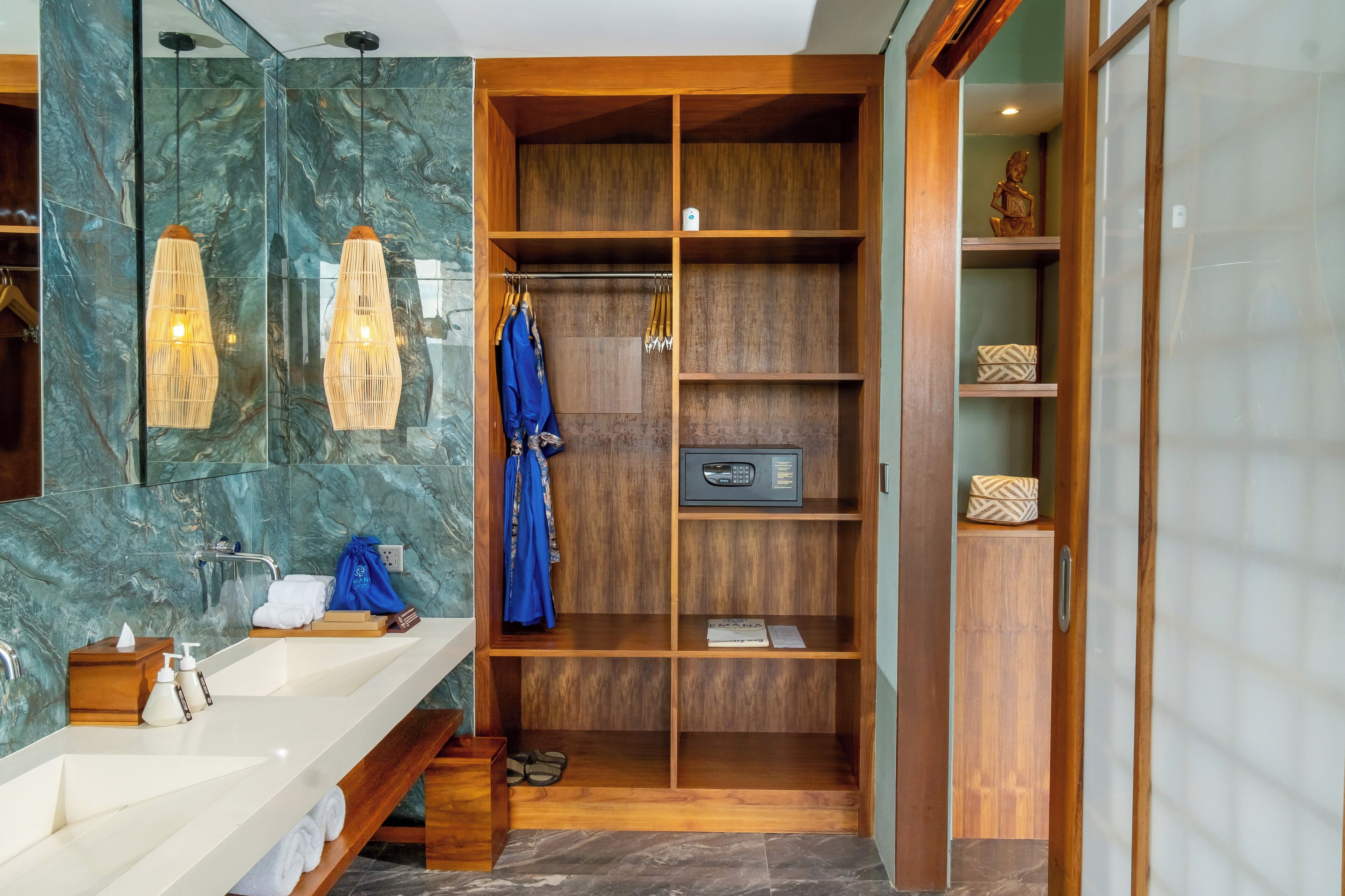 Un baño moderno con salpicadero de mármol, tocador de madera, ducha integrada y armario vestidor con estantes y microondas.