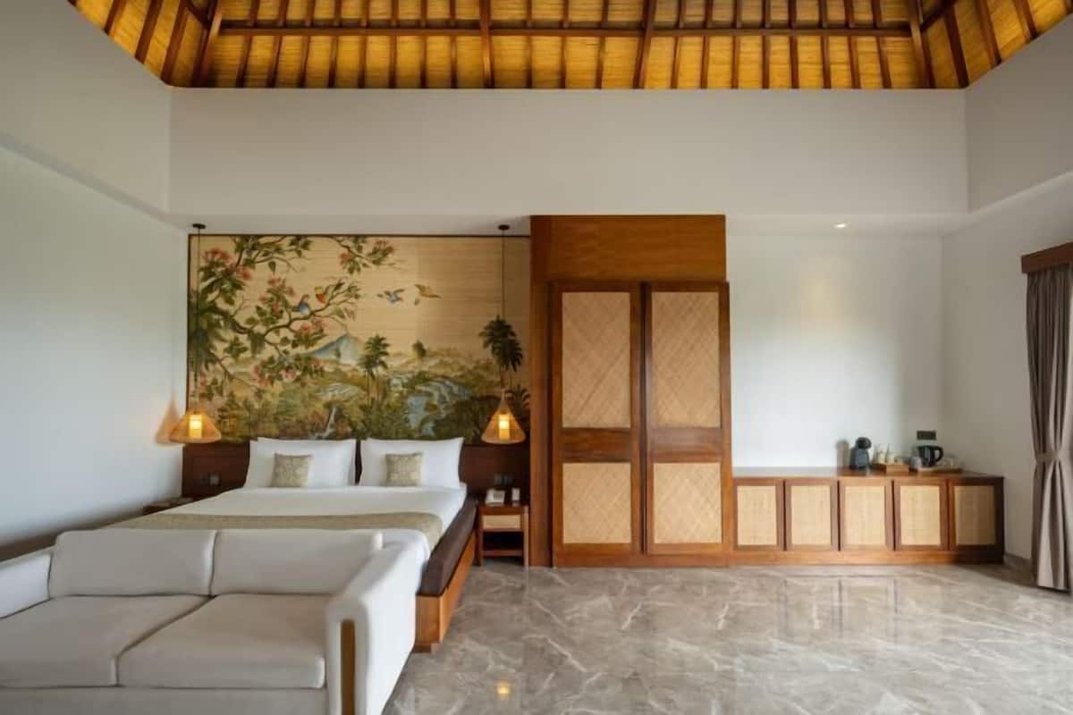 A bedroom with a bed, a sofa, a wooden cabinet, and a mural on the wall.