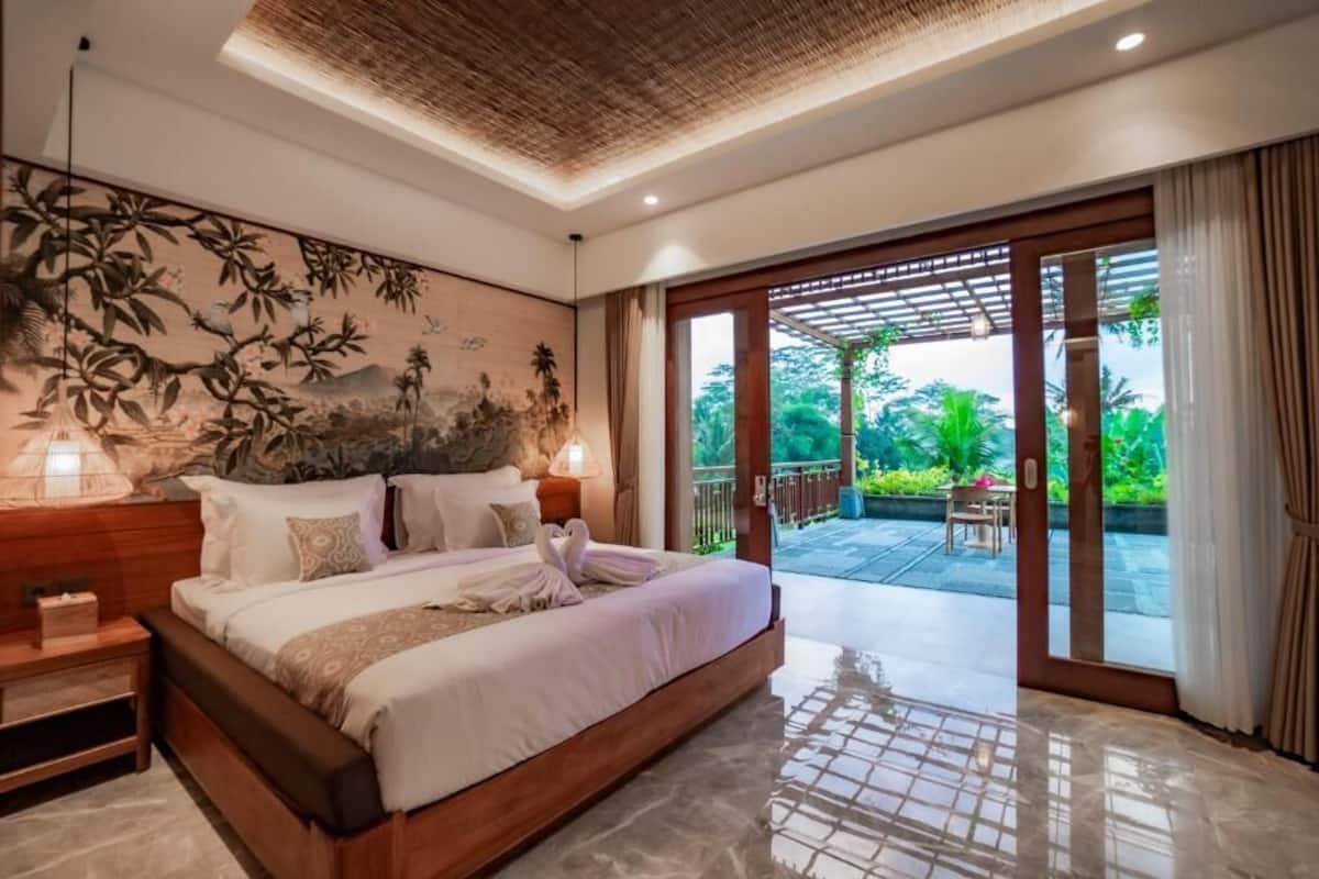 A spacious bedroom with a large bed, a wooden headboard, and a wall mural.