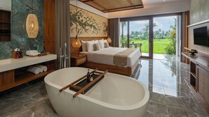 A modern bedroom with a large bed, a bathtub, and a view of a lush garden. - Emana Akatara (Ubud)