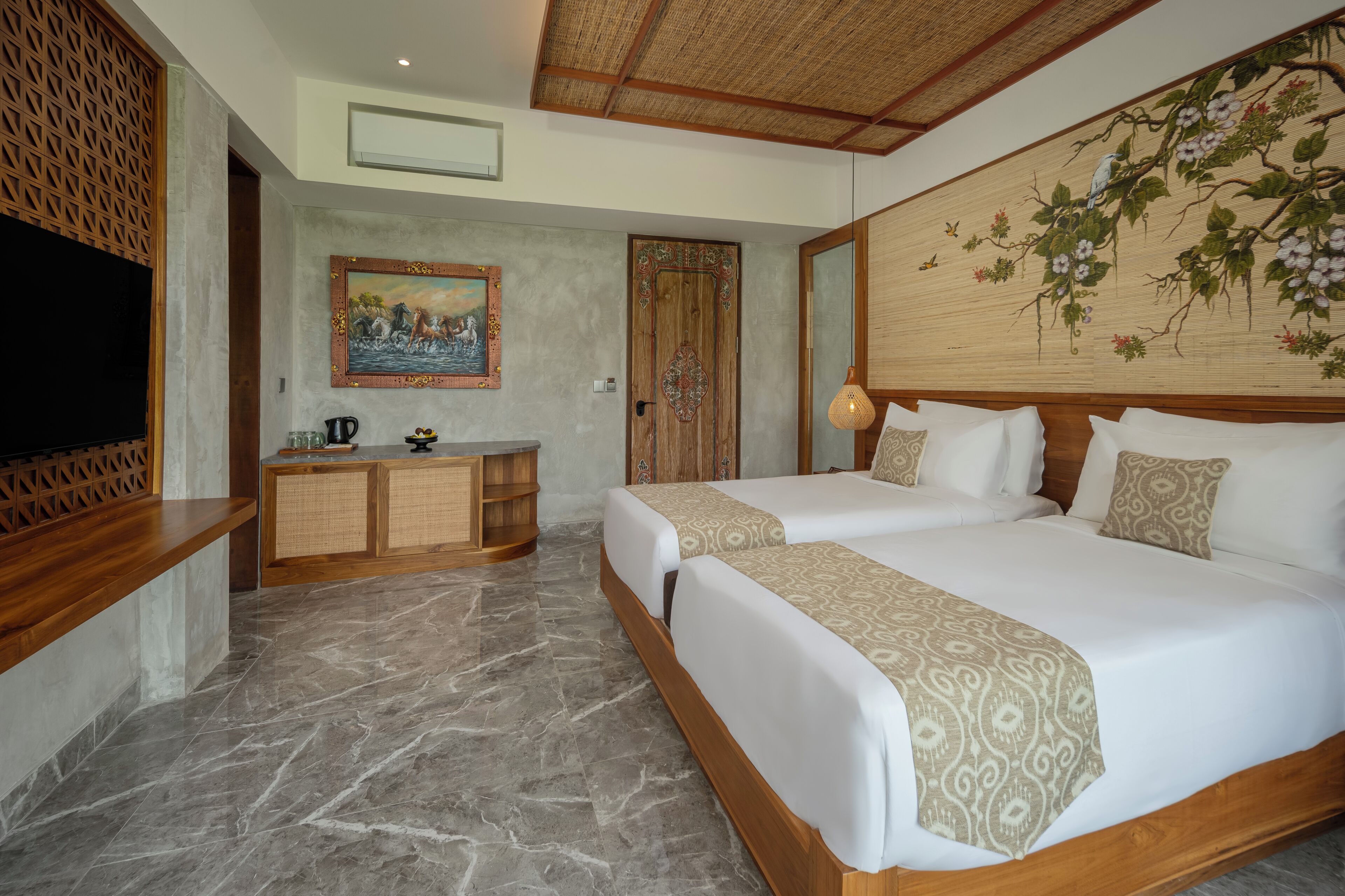 Habitación de hotel con una cama grande, cabecera de madera, un cuadro, un televisor y un escritorio con lámpara.