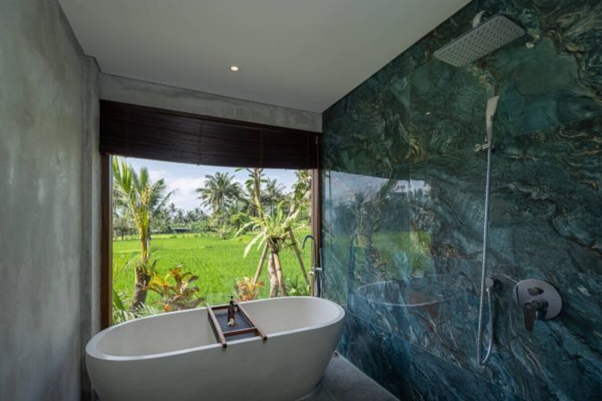 Une salle de bain moderne avec une baignoire sur pieds, une douche et une vue sur un paysage verdoyant.
