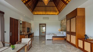 A spacious living area with a high ceiling, a sofa set, a coffee table, and a television. - Emana Akatara (Ubud)