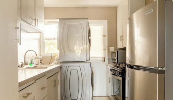 Una cocina moderna con electrodomésticos de acero inoxidable, armarios blancos y un ventanal que proporciona luz natural.