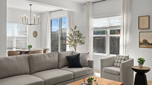 Una sala de estar moderna con un sofá seccional gris, una mesa de centro redonda y un sillón blanco.