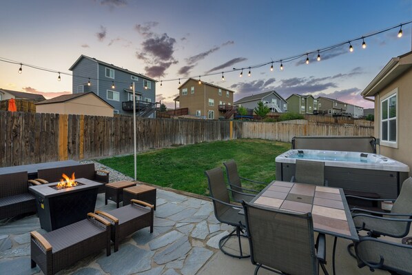 Un patio trasero con una chimenea, mobiliario exterior y un jacuzzi.