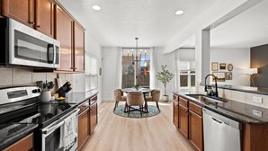 Una cocina moderna con armarios de madera, electrodomésticos de acero inoxidable y una isla central con sillas.