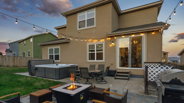 Un patio trasero con una chimenea, mobiliario exterior y una parrilla.