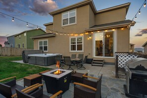 Un patio trasero con una chimenea, mobiliario exterior y una parrilla.