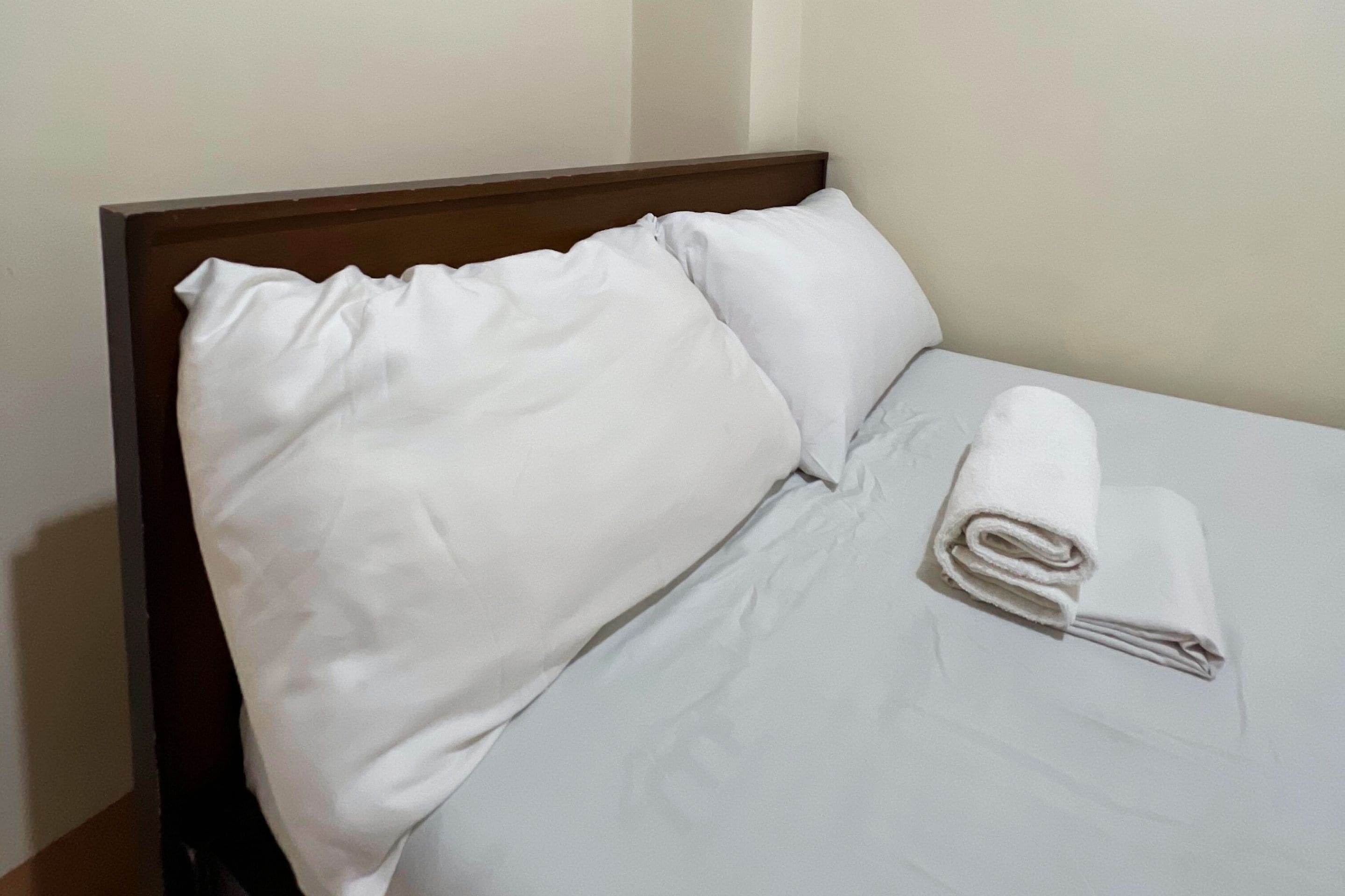 A neatly made bed with white linens and a rolled towel.