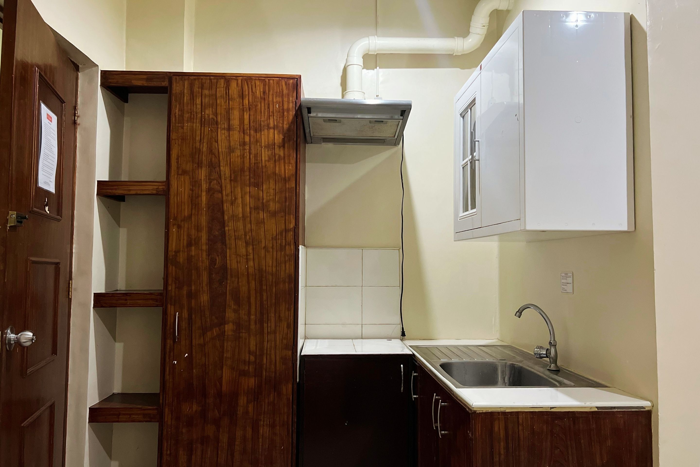 A compact kitchen with a built-in stove, a sink, and wooden cabinets.