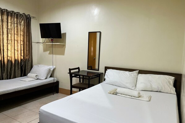 A hotel room with a single bed, a smaller bed, a desk, a chair, a television, and a mirror. - Sta Rosa Inn Iloilo powered by Cocotel (Iloilo)