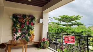 Un balcon avec une table en bois, un banc et une décoration murale florale. Une enseigne indiquant « STA ROSA INN » est visible à l’arrière-plan.