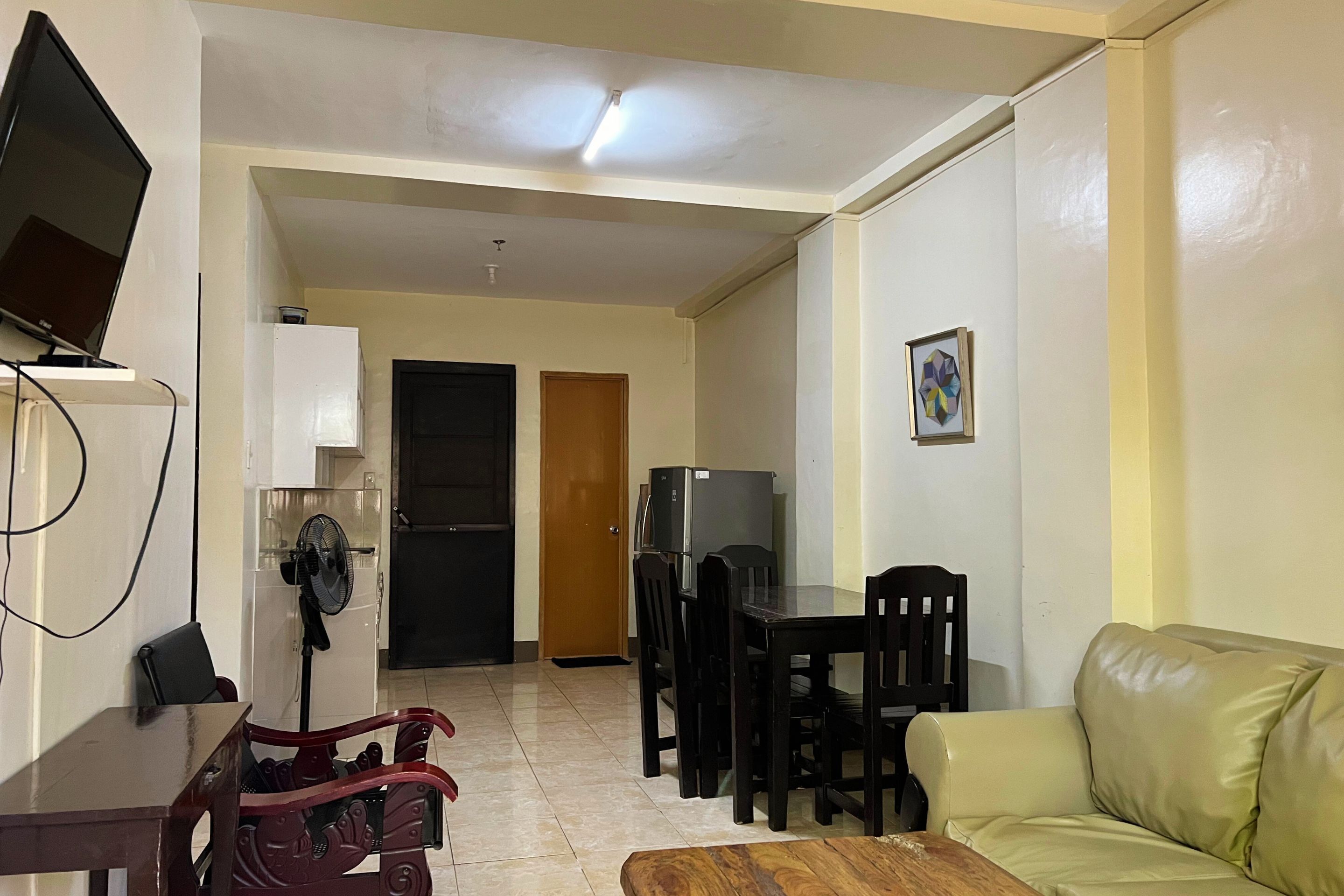 A compact living space with a dining area, a sofa, a TV, and a refrigerator.