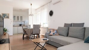 Un salon moderne avec un canapé, une table à manger et des chaises, et un coin cuisine à l’arrière-plan.