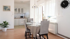 Un espace repas comprenant une table en verre, des chaises et un luminaire suspendu.