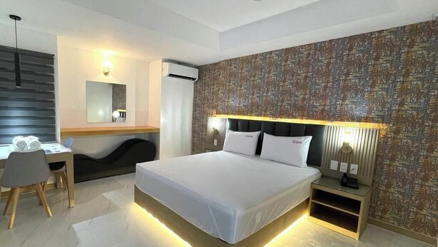 A modern hotel room with a large bed, bedside tables, a desk, and a chair. - Maganda Hotel-San Fernando (Bacolor)