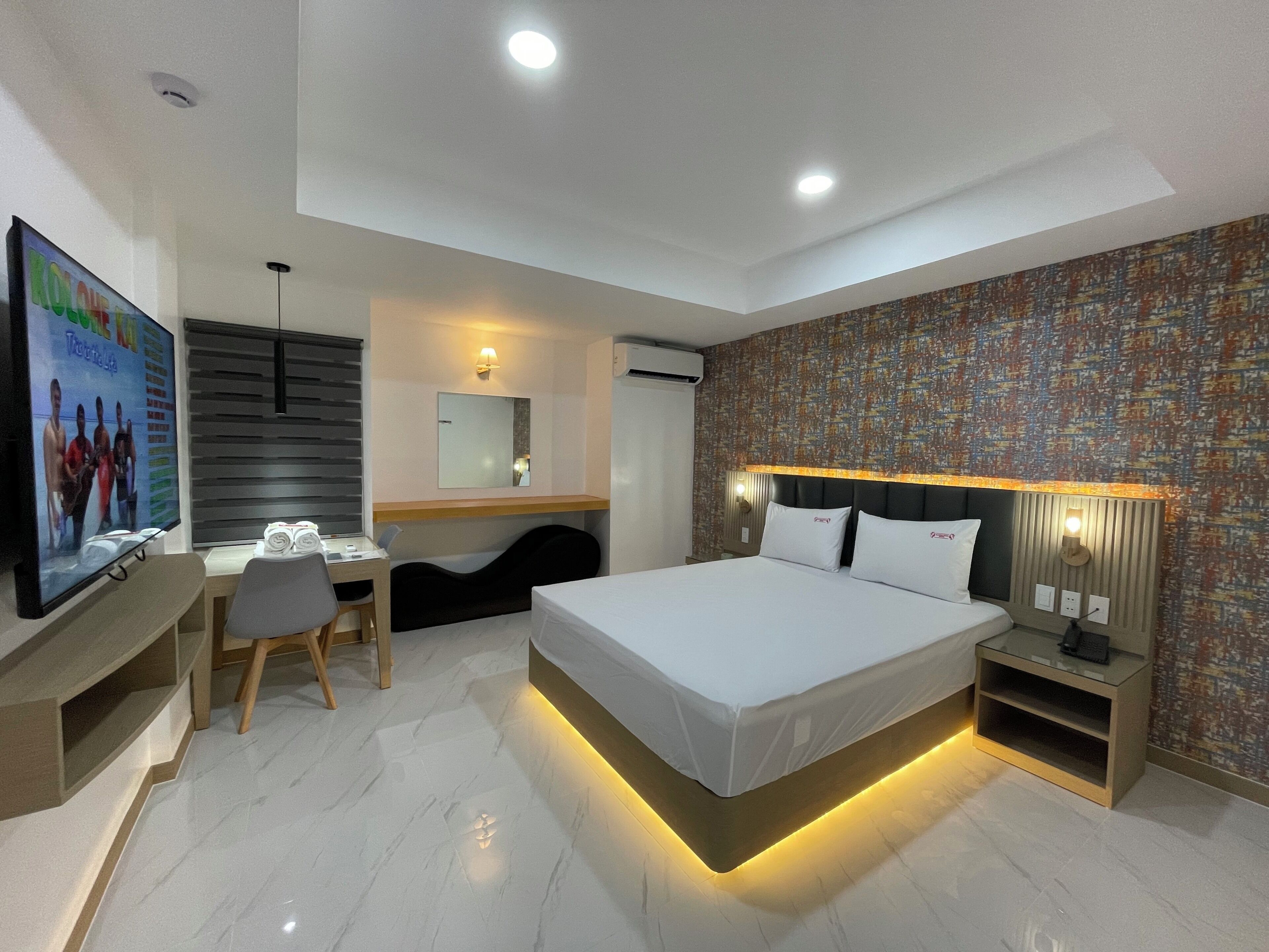 Une chambre d’hôtel moderne équipée d’un lit, d’un bureau, d’une chaise et d’un téléviseur.