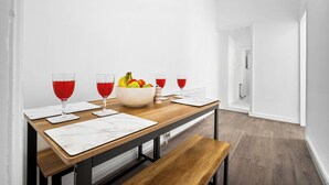 A dining area with a wooden table, marble placemats, and a bowl of fruit. - Apartment 1 Bedroom,Sleeps6,Parking (Birmingham)