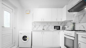 A modern kitchen with white cabinets, a built-in washing machine, a microwave, and an oven. - Apartment 1 Bedroom,Sleeps6,Parking (Birmingham)