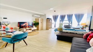 A modern living room with a TV, sofa, dining table, and a large window with curtains. - Inviting To Your Home Near The City Life (Cebu)