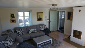 Una sala de estar con un sofá gris, cojines estampados, una mesa de centro y una chimenea.