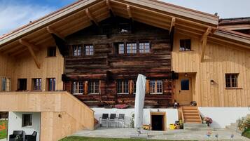 Ein großes Holzgebäude mit geneigtem Dach, zahlreichen Fenstern und einer Treppe, die zum Eingang führt.