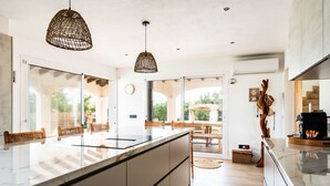 A modern kitchen with a large island, pendant lighting, and a view of the outdoors. - Kistine 5 bedroom villa, Cala Morell (Cala Morell)