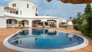 A modern villa with a swimming pool, outdoor seating, and a garden. - Kistine 5 bedroom villa, Cala Morell (Cala Morell)
