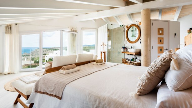 A spacious bedroom with a large bed, a walk-in closet, and a view of the sea. - Kistine 5 bedroom villa, Cala Morell (Cala Morell)