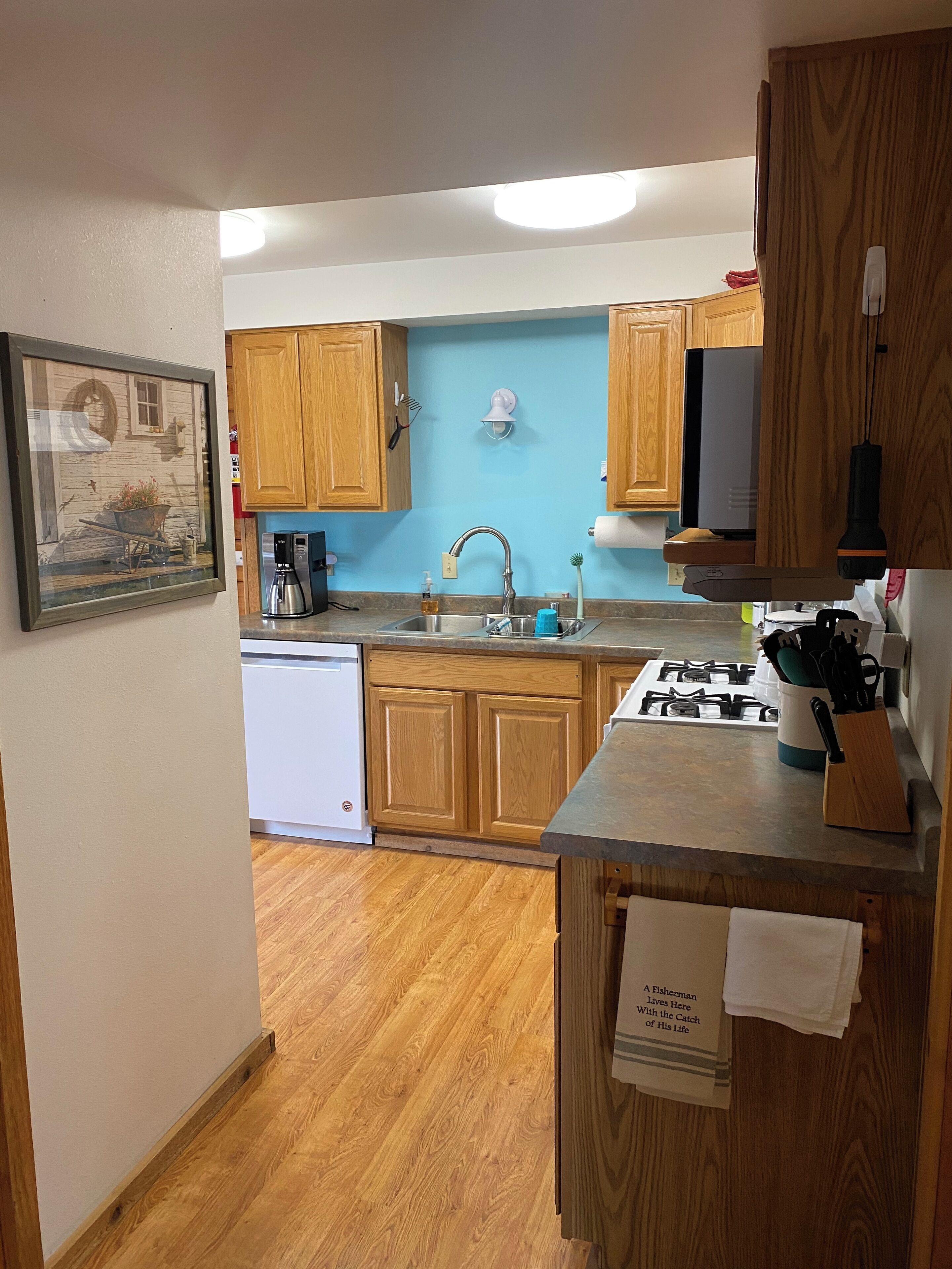 A kitchen with wooden cabinets, a sink, a stove, and a coffee maker.