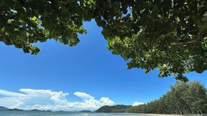 A beach with clear skies, calm water, and a forested area in the background. - 7 Heaven camping Lanta (Ko Lanta)