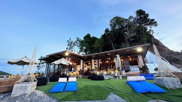 A modern outdoor lounge area with blue loungers, a covered seating area, and a view of a mountainous landscape. - 7 Heaven camping Lanta (Ko Lanta)