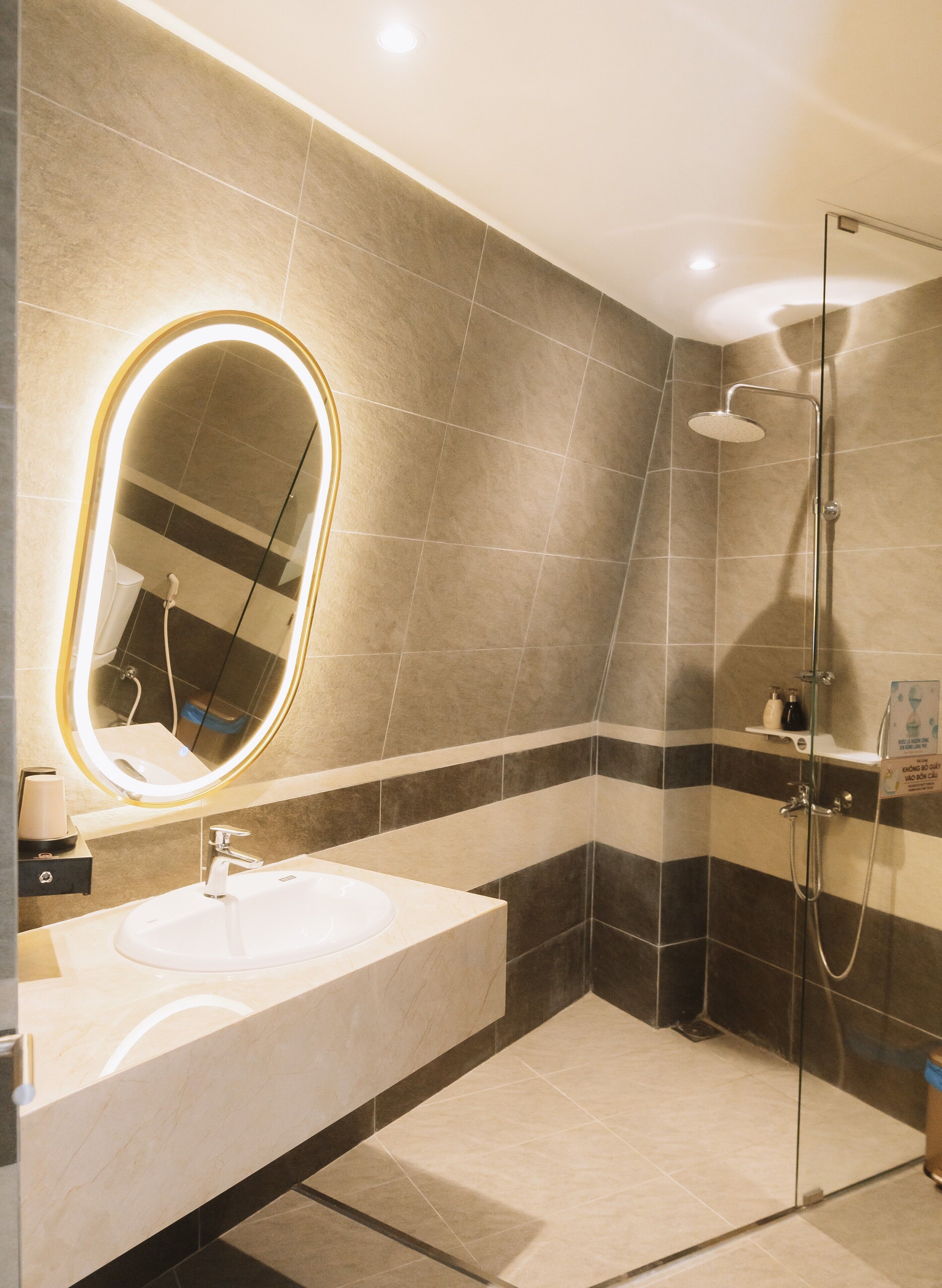 Une salle de bain moderne avec un grand miroir ovale, un lavabo et une douche à parois de verre.